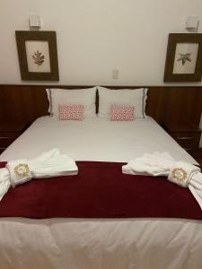 坎波斯杜若尔当Hotel Pousada Bella Locanda的一间卧室配有一张床,上面有两条毛巾