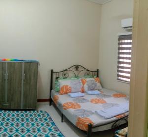 巴西富地Adilah Homestay A的一间卧室配有带橙色和白色枕头的床