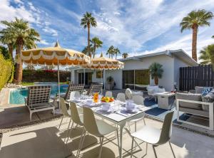 棕榈泉Mid Century Mood House的一个带桌椅的庭院和一个游泳池