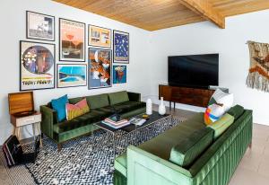 棕榈泉Mid Century Mood House的客厅配有2张绿色沙发和1台平面电视