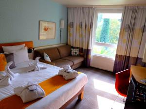 马赛Novotel Marseille Est Porte d'Aubagne的酒店客房设有一张大床和一张沙发。