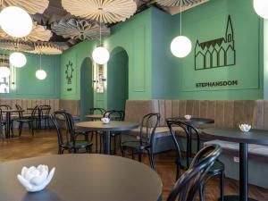 格拉茨ibis Styles Graz Messe的餐厅拥有绿色的墙壁和桌椅