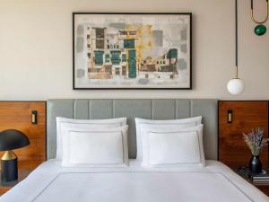 吉达Swissotel Living Jeddah的一张带白色枕头的床和上面的绘画