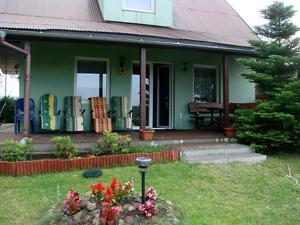 PrzerwankiDom Na Mazurach的庭院里带鲜花门廊的绿色房子