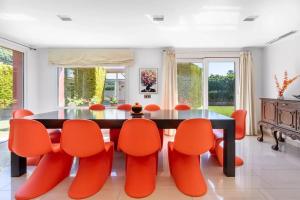 马拉加Ohana Luxury Villa with Heated Pool的一间带桌子和橙色椅子的用餐室