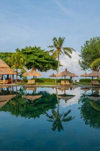 金巴兰Jimbaran Puri, A Belmond Hotel, Bali的度假村的游泳池,配有椅子和遮阳伞