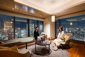 东京THE BLOSSOM HIBIYA的两名女性在享有城市景致的客厅