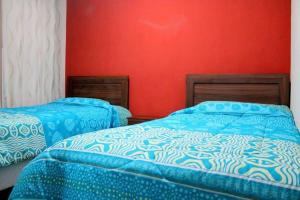 塔尔卡Alojamientos San Sebastián Talca的红色墙壁客房的两张床
