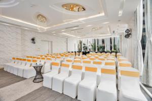 岘港Cicilia Hotels & Spa Danang Powered by ASTON的一间会议室,配有白色和橙色椅子