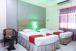 吉大港Hotel Golden Inn Chattagram Ltd的一间设有两张床、一张桌子和一把椅子的房间