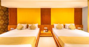 DharmpuraShamrock Greens by Jardin Hotels的两张床位于带黄色墙壁的酒店客房