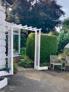 Ben RhyddingThe Little Acorn的花园内白色的凉棚,设有长凳