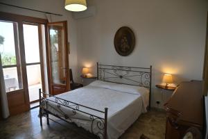普尔萨诺B&B Villa Dongiovanni的一间卧室设有一张床、一个窗口和一个时钟
