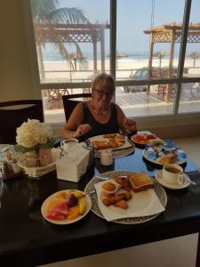 塞拉莱塞拉莱海滩度假酒店的坐在餐桌旁吃一盘早餐食品的女人