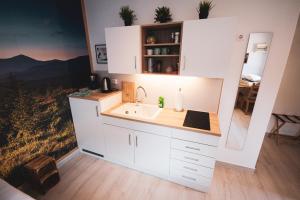 克拉根福西北一室公寓的厨房配有白色橱柜和水槽