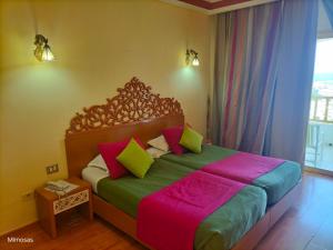 塔巴卡Hôtel LES MIMOSAS TABARKA的一间卧室配有一张带色彩缤纷枕头的大床
