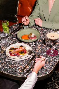 墨尔本墨尔本汇合酒店的两人坐在餐桌上,一边吃盘子