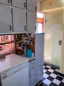 维里尔·杜·拉克Chambre privée dans Maison Familiale的厨房配有白色橱柜和 ⁇ 格地板