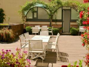 巴塞罗那Hotel Turin Barcelona的庭院配有白色的椅子和桌子,鲜花盛开