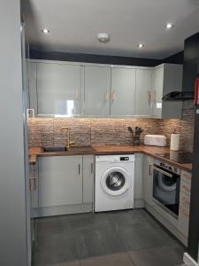 考文垂Beautiful Modern Coventry City Centre Apartment的厨房配有洗衣机和水槽