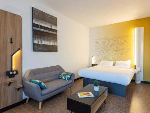 布吕兹B&B HOTEL Rennes Parc Expo Aéroport的酒店客房,配有床和沙发