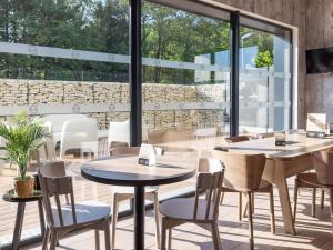 布吕兹B&B HOTEL Rennes Parc Expo Aéroport的餐厅设有桌椅和大窗户。
