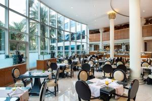 迪拜喜来登朱美拉海滩度假酒店的餐厅设有桌椅和窗户。