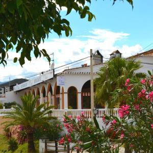 马拉加Habitacion rural en Alora Caminito del Rey的白色的建筑,有棕榈树和粉红色的花