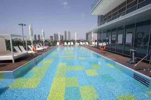 特拉维夫Midtown Tel Aviv Luxury Apartment的一座大型游泳池,位于一座建筑的一侧,拥有蓝色和绿色的瓷砖