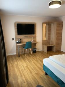 海姆巴赫Art Hotel Eifel的酒店客房配有一张床、一张书桌和一台电视。