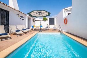 阿尔布费拉Villa Belize by Algarve Vacation的一座带椅子和遮阳伞的游泳池位于大楼旁