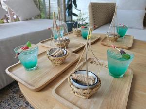 奥南海滩The Pin Boutique Pool Villa Krabi的一张桌子,上面有四个盘子,上面有蓝色的饮料和篮子