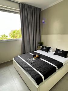 巴特亚姆Motel Hofim的一间卧室配有一张带黑白床单的床和一扇窗户。