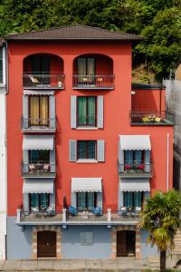 梅利德76 The Lake House - Lugano的带阳台的红色建筑和棕榈树