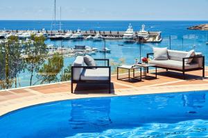 圣蓬萨普瑞斯特博阿德里亚诺酒店 - 仅限成人的水边的游泳池配有两把椅子和一张桌子