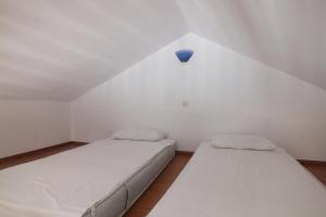 锡米Anastasia Apartments (Chorio)的白色小客房内的两张床,配有蓝色灯泡