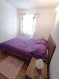 洛夫兰Apartment in Lovran的一间小卧室,配有一张紫色的床和一张桌子