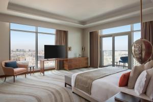 多哈Abesq Doha Hotel and Residences的酒店客房,配有床和电视
