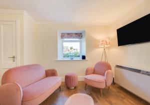 托基Honey Cottage Mews的客厅配有粉色椅子和平面电视