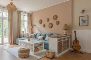 索波特Agapella Apartamenty- Sopot Cottage Ogród 400m od plaży 6 dorosłych i dzieci的客厅配有蓝色沙发和吉他