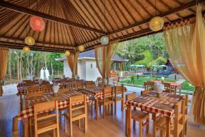 珀尼达岛Mahaloka Valley Nusa Penida的一间带木桌和椅子的餐厅以及庭院
