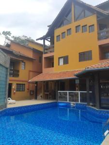 卡拉瓜塔图巴Pousada Morada Dusanjos的一座别墅,在一座建筑前设有一个游泳池