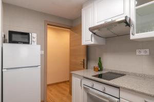 里瓦德塞利亚Belmonte, apartamento en Ribadesella的厨房配有白色橱柜和白色冰箱。