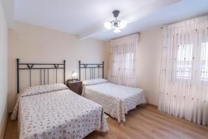 里瓦德塞利亚Belmonte, apartamento en Ribadesella的卧室设有两张床,拥有白色的墙壁和木地板