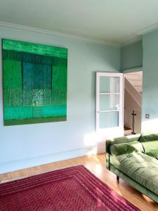 伦敦Home in Chiswick Homefields的客厅配有沙发和墙上的绘画