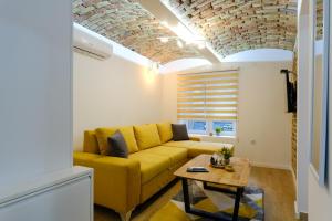 萨拉热窝All seasons apartments Sarajevo with free parking的客厅配有黄色的沙发和桌子