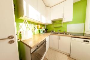 沙蒂永La Cuccia • Magnifique F2 super équipé的厨房配有白色橱柜和绿色墙壁