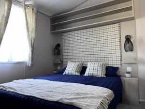 PerranzabuloePorthcurno 4, Silverbow Country Park的一间卧室配有一张带蓝色床单的床和一扇窗户。