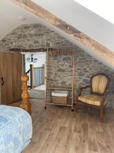 LlanwrdaPippin Lodge的一间卧室设有石墙、一张床和一把椅子