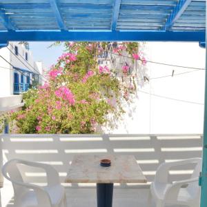纳克索乔拉Asiminas的庭院里摆放着一张桌子和椅子,上面摆放着粉红色的鲜花